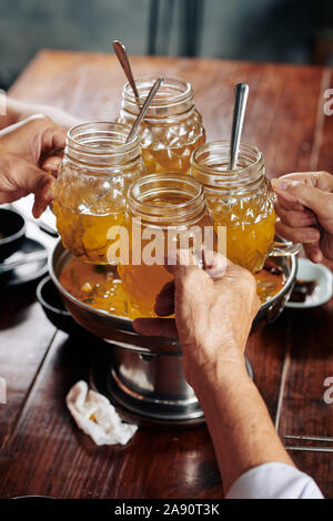 Close-up immagine di amici tintinnio tazze con ale su metallo con ciotola di zuppa Foto Stock
