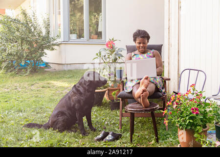 Donna sorridente nel giardino con laptop Foto Stock