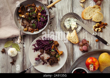Piatto di carne di cervo sul vecchio tavolo in legno, con marmellata di frutta, formaggio e castagne, tradizionale piatto invernale con carne, bottino di caccia Foto Stock
