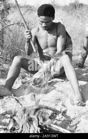 Botswana: Un Naro-Buschmen vicino a Ghanzi e prateria Safari Lodge è la tostatura un melone. Foto Stock