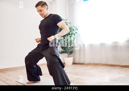 L uomo è impegnato nel karate in hall contro il fondale di pianta verde durante il giorno Foto Stock