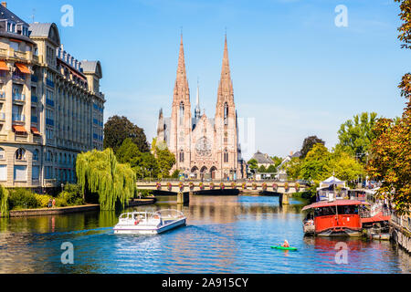 La facciata della chiesa di san Paolo sulle rive del fiume Ill a Strasburgo, Francia, con un kayaker e un tour in barca crociera. Foto Stock