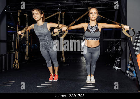 Close-up di due full-length atletiche di giovani donne che esercitano con stirata elastica in palestra Foto Stock