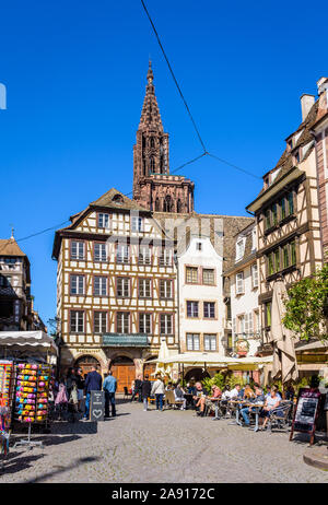 Turisti che si godono il patrimonio medievale e caffetterie lungo la strada nel quartiere storico di Strasburgo, Francia, a pochi passi dalla cattedrale di Notre Dame. Foto Stock