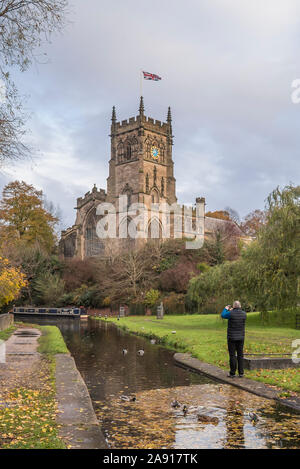 Kidderminster, Regno Unito. 12 Novembre, 2019. Regno Unito: meteo dopo un altro freddo e umido in start Worcestershire, l'autunno sunshine fa un aspetto di benvenuto. La Chiesa di Santa Maria (la chiesa parrocchiale di Kidderminster) sta meravigliosamente illuminati lungo il pittoresco canale come un pedone locale si ferma per catturare il momento, fotografando la scena sul suo telefono cellulare. Credito: Lee Hudson/Alamy Live News Foto Stock