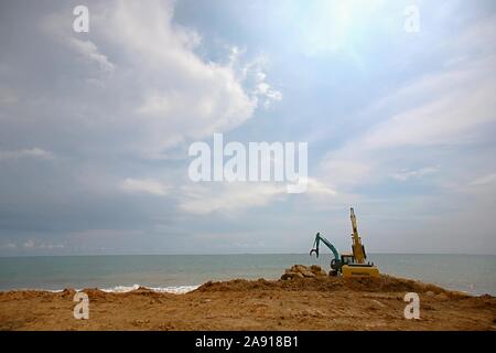 Escavatore parcheggiato in riva al mare a costruzione area di progetto. Foto Stock