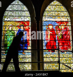 Vetro testa conservatore Sam Kelly ispeziona i Angeli Laudantes e Angeli Ministrantes vetrate a Cattedrale di Salisbury come lavori di restauro per pulire, conservare e ripristinare le finestre, installato nel 1879, ottiene in corso. Foto Stock