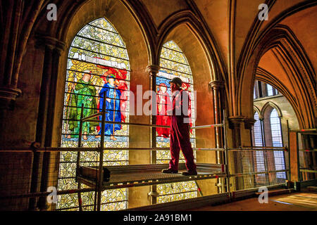 Vetro testa conservatore Sam Kelly ispeziona i Angeli Laudantes e Angeli Ministrantes vetrate a Cattedrale di Salisbury come lavori di restauro per pulire, conservare e ripristinare le finestre, installato nel 1879, ottiene in corso. Foto Stock