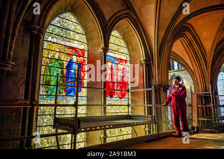 Vetro testa conservatore Sam Kelly ispeziona i Angeli Laudantes e Angeli Ministrantes vetrate a Cattedrale di Salisbury come lavori di restauro per pulire, conservare e ripristinare le finestre, installato nel 1879, ottiene in corso. Foto Stock