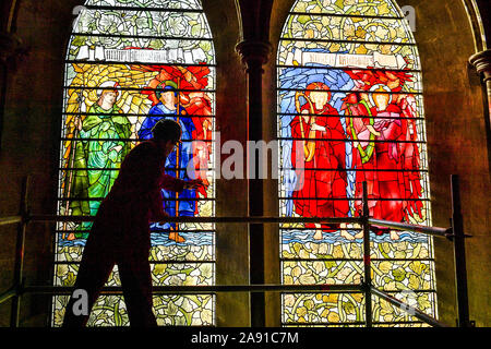 Vetro testa conservatore Sam Kelly ispeziona i Angeli Laudantes e Angeli Ministrantes vetrate a Cattedrale di Salisbury come lavori di restauro per pulire, conservare e ripristinare le finestre, installato nel 1879, ottiene in corso. Foto Stock