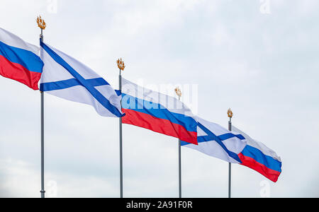 Alfieri della marina russa e le bandiere della Russia sono sventolare sul vento sotto il blu cielo nuvoloso. Parata militare decorazione, San Pietroburgo, Russia Foto Stock