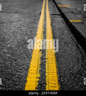 Parcheggio limitato, Close Up doppia luminosa linee di colore giallo su fondo bagnato e Rainy day - Norwich, Regno Unito Foto Stock