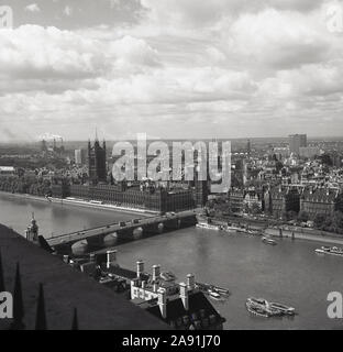 Degli anni Cinquanta, storico vista aerea sul fiume Tamigi e una vista del Palazzo di Westminster e le case del parlamento del governo britannico, Londra, Inghilterra, Regno Unito. In lontananza i comignoli fumanti di Battersea Power Station può essere visto. Foto Stock