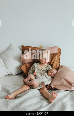 Ragazza con i gemelli neonati sul letto Foto Stock