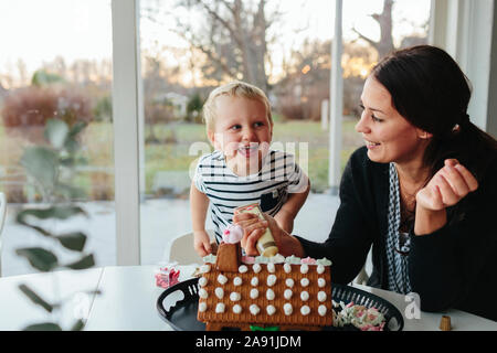 Madre e figlio decorare gingerbread house Foto Stock