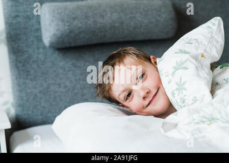 Ragazzo nel letto guardando la fotocamera Foto Stock