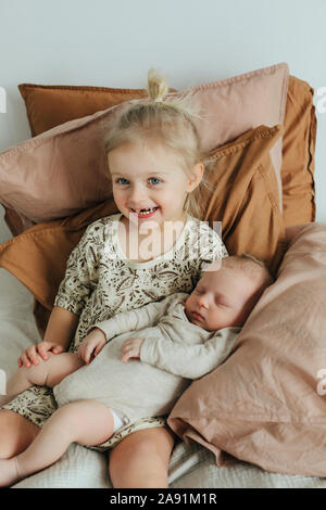 Ragazza con i gemelli neonati sul letto Foto Stock