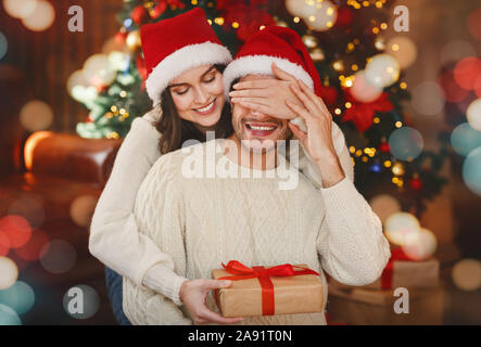 Sorridente giovane donna dando marito regalo di natale Foto Stock