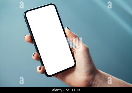 Mockup immagine di donna di mano azienda cornici sottile telefono cellulare con schermo bianco lucido in ambiente aziendale - Immagine Foto Stock