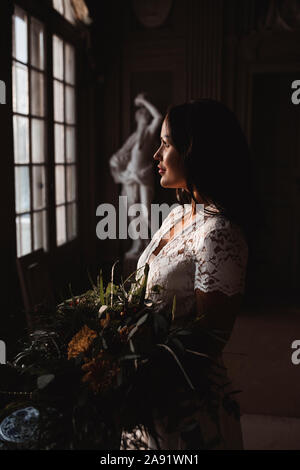 Sposa guardando attraverso la finestra Foto Stock