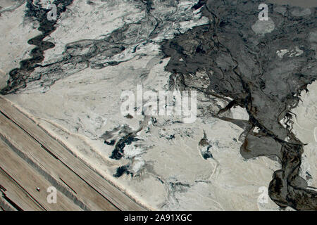 Prelevare i carrelli passano attraverso uno degli enormi bacini di stoccaggio in Fort McMurray in Alberta, Canada. Gli stagni sono fra il più grande uomo fatto di strutture in tutto il mondo, lo spanning di più di 175 chilometri quadrati. Essi pongono una sfida aggiunto all'olio sands produzione: anche dopo aver terminato la produzione, può richiedere fino a trenta anni per il limo negli stagni di essiccare. L'acqua inquinata è tossico per qualsiasi delle creature viventi. L'Athabasca oil sands deposito è tra le più grandi del mondo. Il bitume, anche comunemente denominato tar (quindi tar sands), contiene un sacco di idrocarburi, ma è notoriamente difficile da ext Foto Stock