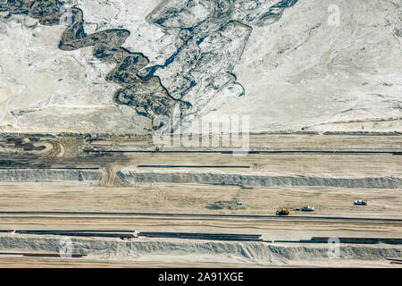 Prelevare i carrelli passano attraverso uno degli enormi bacini di stoccaggio in Fort McMurray in Alberta, Canada. Gli stagni sono fra il più grande uomo fatto di strutture in tutto il mondo, lo spanning di più di 175 chilometri quadrati. Essi pongono una sfida aggiunto all'olio sands produzione: anche dopo aver terminato la produzione, può richiedere fino a trenta anni per il limo negli stagni di essiccare. L'acqua inquinata è tossico per qualsiasi delle creature viventi. L'Athabasca oil sands deposito è tra le più grandi del mondo. Il bitume, anche comunemente denominato tar (quindi tar sands), contiene un sacco di idrocarburi, ma è notoriamente difficile da ext Foto Stock