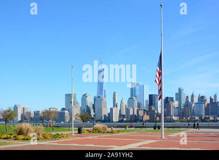 Città di Jersey, New Jersey - 04 NOV 2019: Semi-montante bandiera americana a Liberty State Park con la Manhattan, skyline di New York e il fiume Hudson in Foto Stock