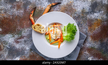 Cibo banner web. Close-up con insalata di neve con la polpa di granchio, avocado e verdure. Servire su un tovagliolo grigio e un background arrugginito Foto Stock