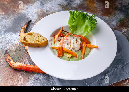 Close-up con insalata di neve con la polpa di granchio, avocado e verdure. Servire su un tovagliolo grigio e un background arrugginito Foto Stock