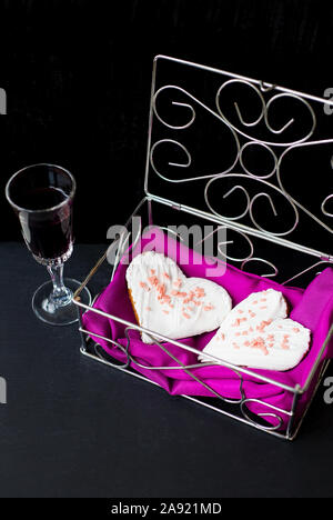 Bicchiere di vino e biscotti a forma di cuore si trova in uno scrigno. Foto Stock