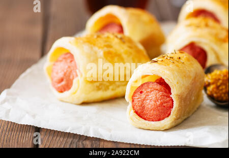 Suini in un planket - pasta sfoglia panini con salsicce su un sfondo di legno. Fast food o snack concetto. Foto Stock