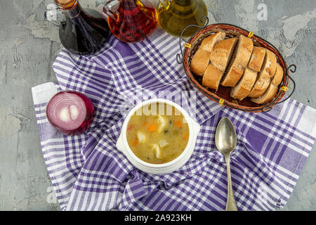 Il Minestrone, italiano zuppa di verdure servita con ravioli turco su sfondo grigio. Foto Stock