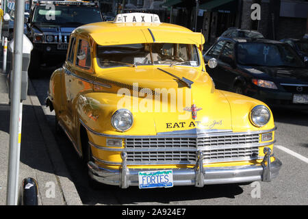 Un classico Vintage NYC giallo Taxi, mangiare a Joes, Fortes, parcheggiata lungo una strada di Vancouver, British Columbia, Canada, 2013 ore diurne Foto Stock