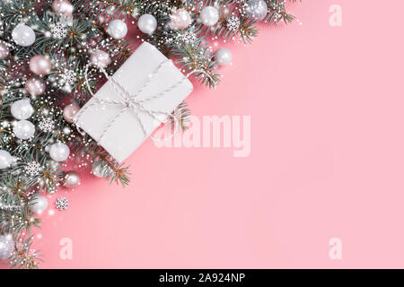 Natale composizione pastello con regalo bianca su sfondo rosa. Xmas frame con spazio per il testo. Vista da sopra. Piatto stile di laici. Foto Stock