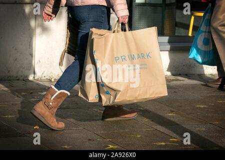Una donna che porta una carta Primark shopping borsa di trasporto carta riciclata al 100% riutilizzabile sacchetti del supermercato per la vita Foto Stock