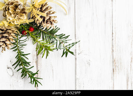 Bianco sullo sfondo di legno con decorazione di Natale, pigne appeso sul ramo dell albero di natale Foto Stock