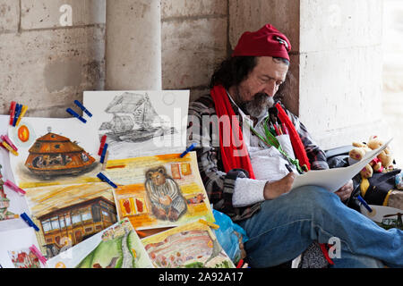 Budapest, Ungheria - 26 Maggio 2019: street artista seduto e schizzi su un nuovo lavoro Foto Stock