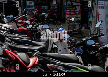 KRABI, Tailandia - 10 luglio 2019. Affollati parcheggio posto in Krabi con piena di motociclette. Un sacco di moto parcheggio nelle righe sul marciapiede in Foto Stock