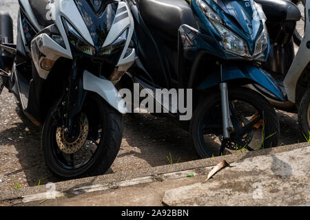 KRABI, Tailandia - 10 luglio 2019. Affollati parcheggio posto in Krabi con piena di motociclette. Un sacco di moto parcheggio nelle righe sul marciapiede in Foto Stock