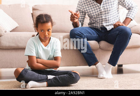 Strict afro padre scolding poco disobbediente la figlia per cattivo comportamento Foto Stock