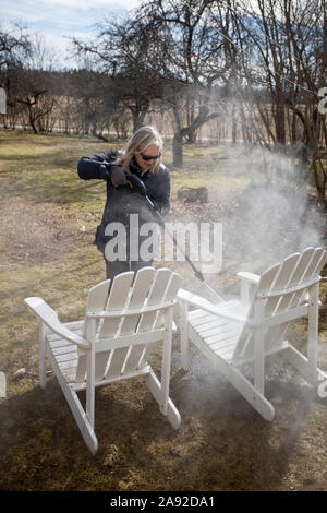 Donna di pulizia in sedie da giardino Foto Stock