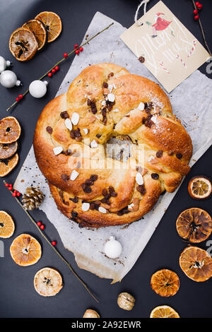 Appena sfornato rotolo chrismtas corona su un sfondo di legno con varie decorazioni natalizie Foto Stock