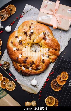 Appena sfornato rotolo chrismtas corona su un sfondo di legno con varie decorazioni natalizie Foto Stock