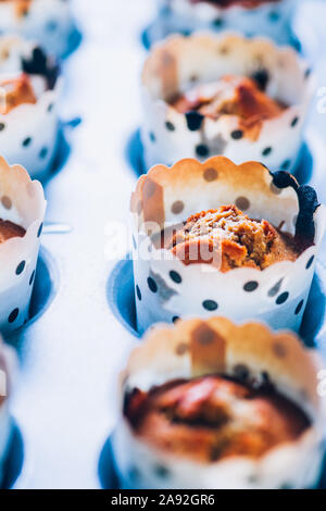 In prossimità di alcuni appena sfornato di zucca muffin rivestiti su un alluminio vassoio da forno per la Festa di halloween visualizzata su un blu scheda rustico, laici piatta vista dall'alto,nat Foto Stock