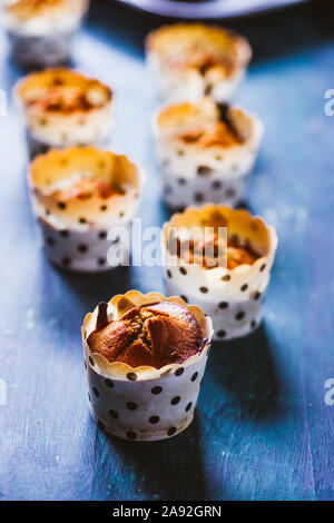 In prossimità di alcuni appena sfornato di zucca muffin rivestiti su un alluminio vassoio da forno per la Festa di halloween visualizzata su un blu scheda rustico, laici piatta vista dall'alto,nat Foto Stock