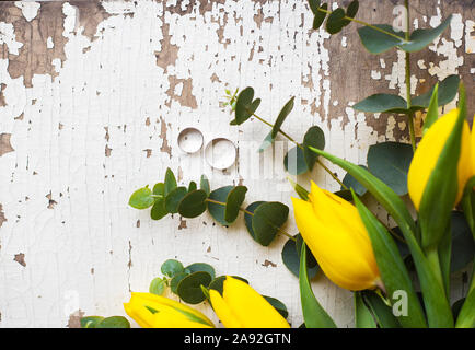 Gli anelli di nozze con tulipani gialli sul vecchio tavolo bianco Foto Stock