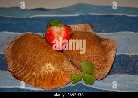 Integrale di fresco e sano dolce empanadas ripiene di color oro, confettura di fragole Foto Stock