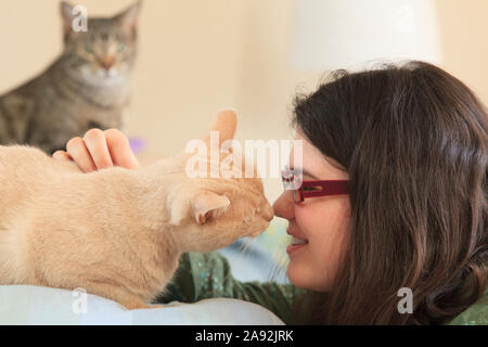 Donna con la sindrome di Asperger giocando con il suo animale domestico gatti Foto Stock