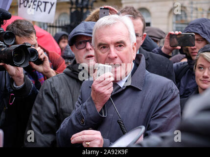 Westminster, Londra, Regno Unito. 12 novembre 2019. John McDonnell, manodopera MP e ombra il Cancelliere dello Scacchiere rivolgendosi al McDonalds dipendenti dalla regione di Londra colpisce nella parte anteriore del 10 Downing strade riforme promettenti come parte di un governo laburista di aumentare i salari minimi e proteggere i tassi dei lavoratori poveri. Cartello con la 'Povertà' in background Credito: JF Pelletier / Alamy Live News Foto Stock