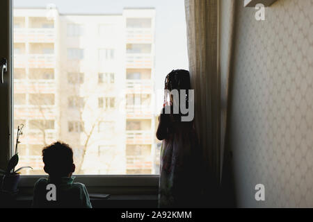 Ragazza guardando attraverso la finestra Foto Stock